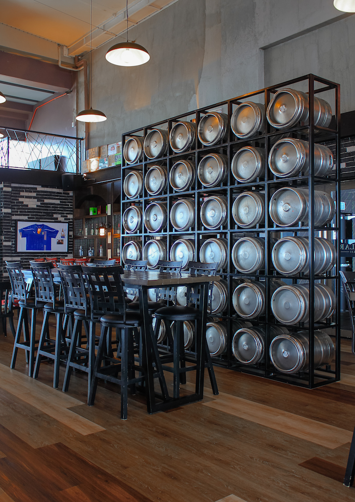 At the center of the bar, there is a wall made out of beer kegs
