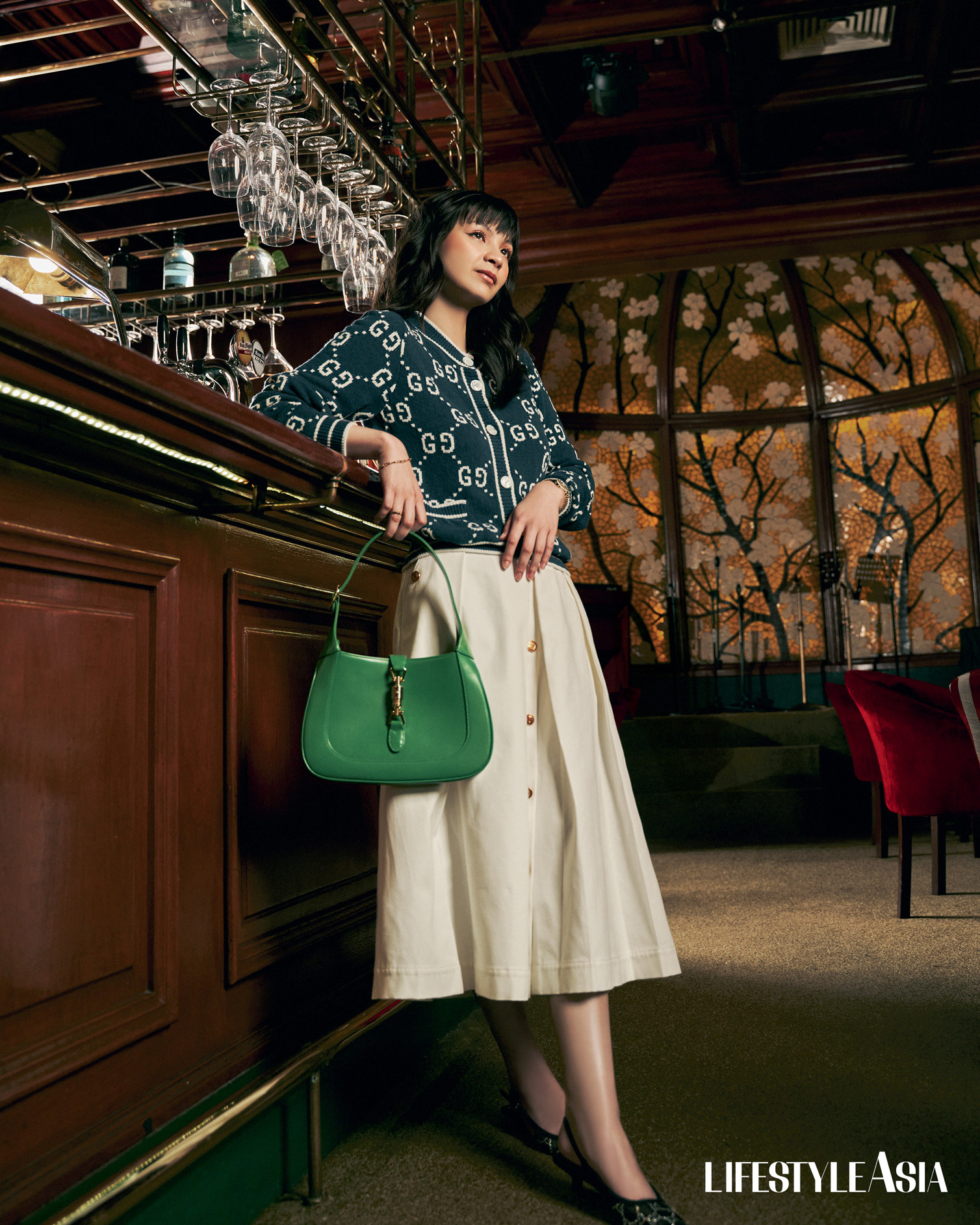On Kyle: GG Cotton Jacquard Cardigan, Cotton Canvas Skirt With Pleats, Gucci Jackie 1961 Bag With Piston Closure In Green, Women’s GG Slingback Pump, Gucci Link To Love Ring and Bracelet, and G-timeless Watch In 29mm, all from GUCCI.