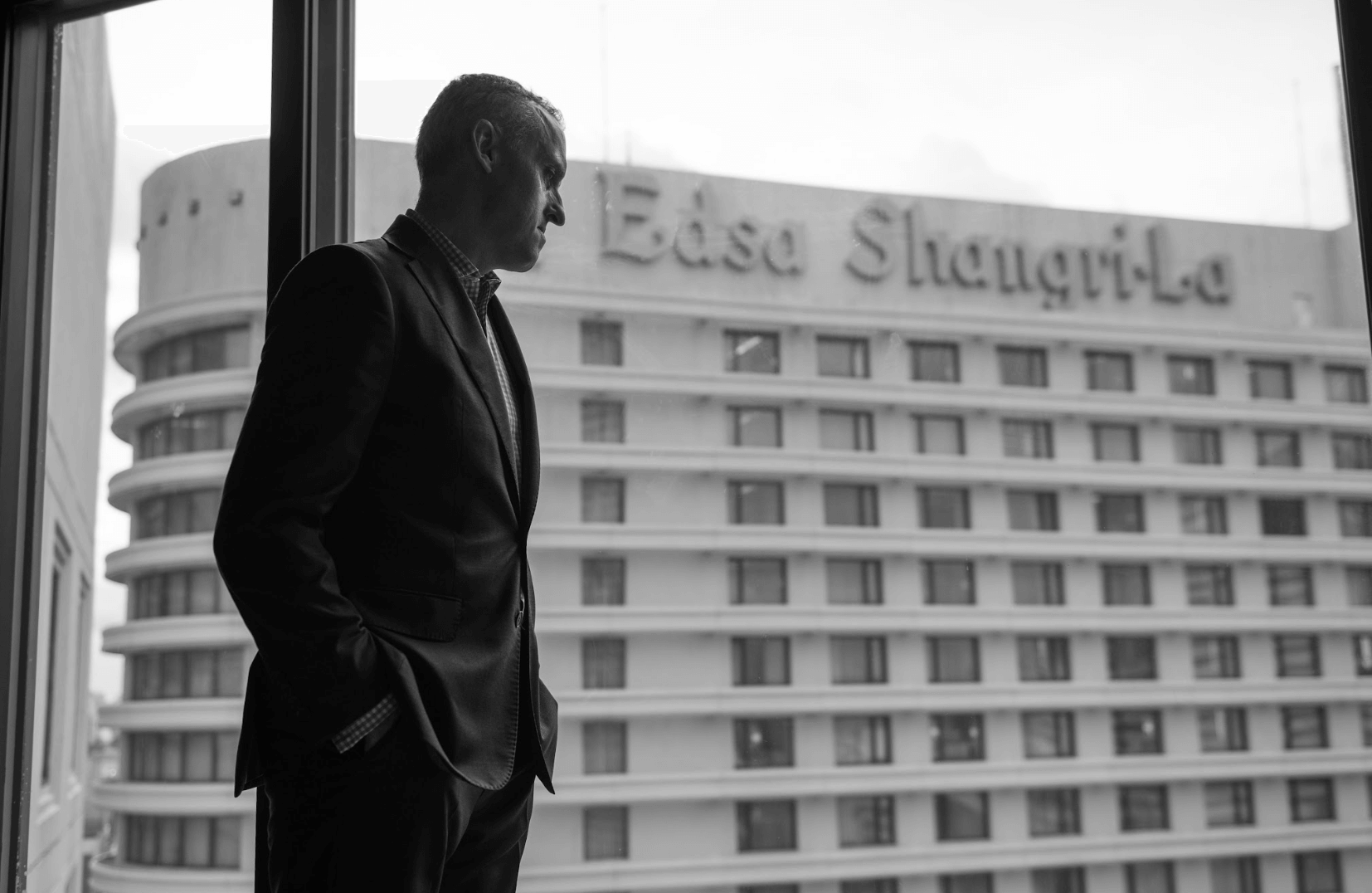 Behind Jonathan Reynolds is a big logo of Edsa Shangri-La