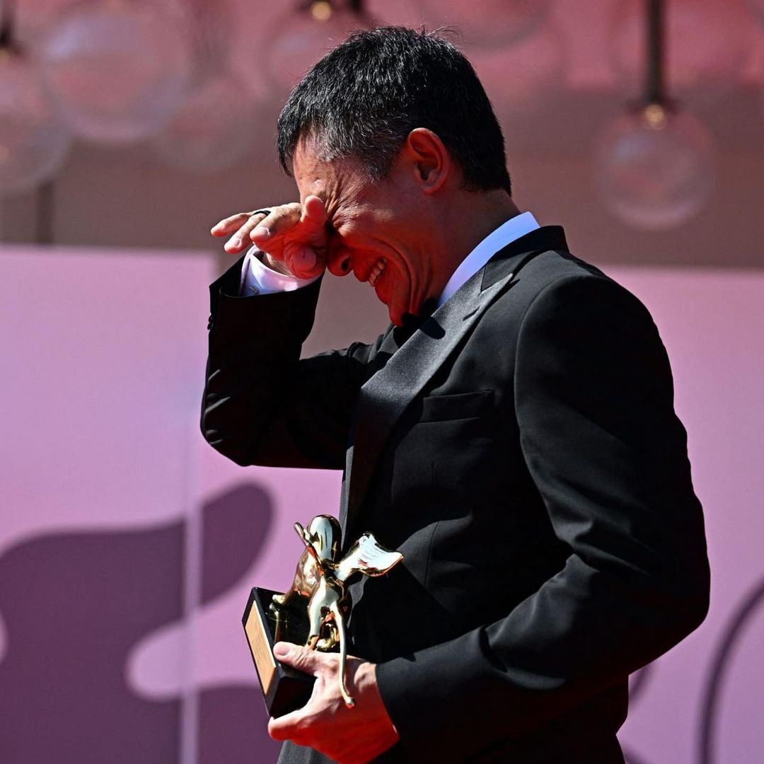 Tony Leung accepts the Golden Lion as he wipes tears from his eyes