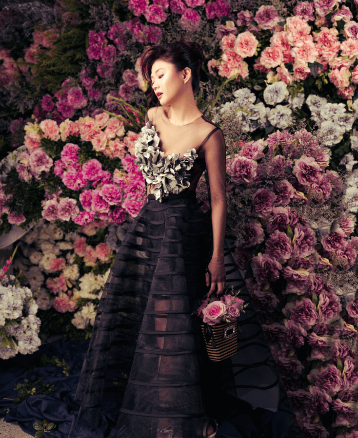 Black tulle long sleeved sheer top with handcrafted silk and tulle petals, and sheer hoop skirt with gossamer strips, both by JO RUBIO. Raffia woven basket bag, ROGER VIVIER.