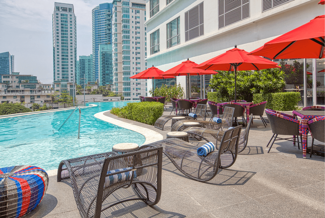 The infinity pool with chaises and sets of tables and chairs in Novotel Suites Manila at Acqua