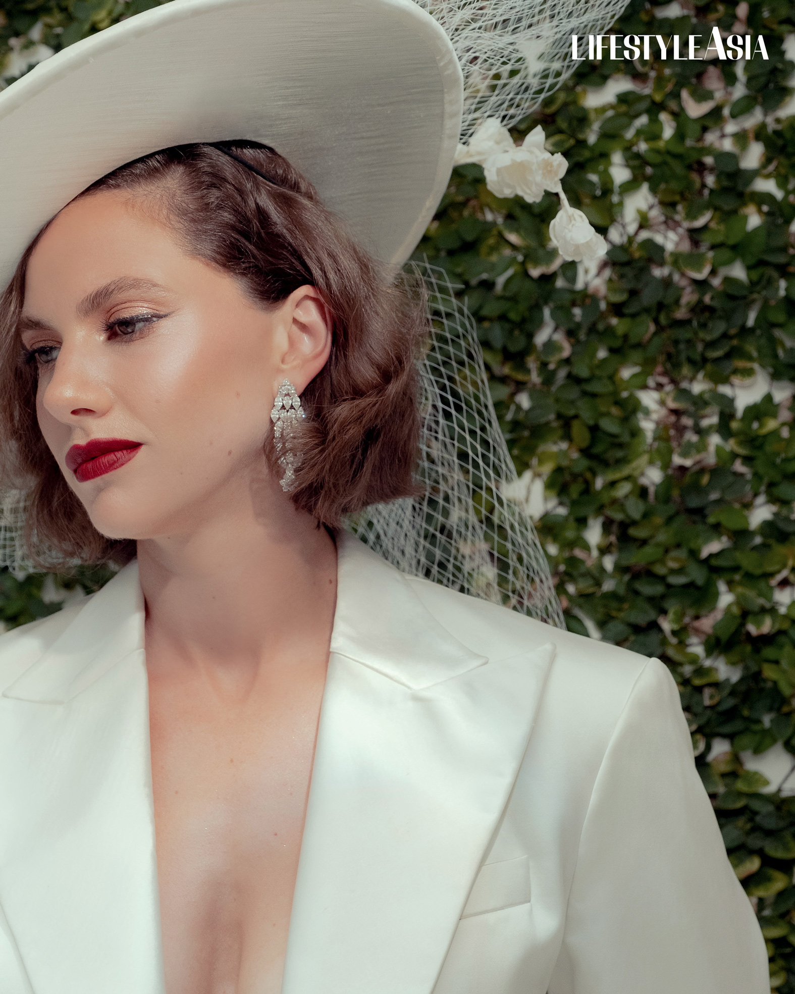 White cropped satin tuxedo jacket with matching silk skirt and hat, JAGGY GLARINO; Diamond drop earrings, JUL B DIZON JEWELLERY.