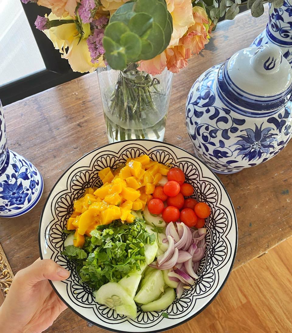 A vibrant fresh salad of mangoes, coriander, cherry tomatoes, red onions, and cucumbers, all from Maria's Table