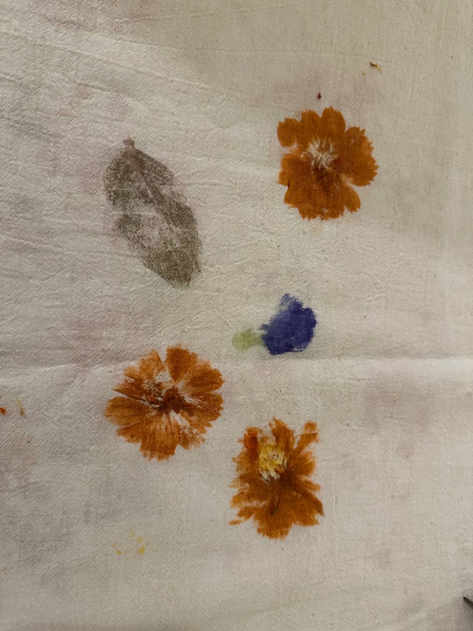 Pressing flowers on a canvas, made possible with a piece of leaf and a hammer, as demonstrated at the exhibit