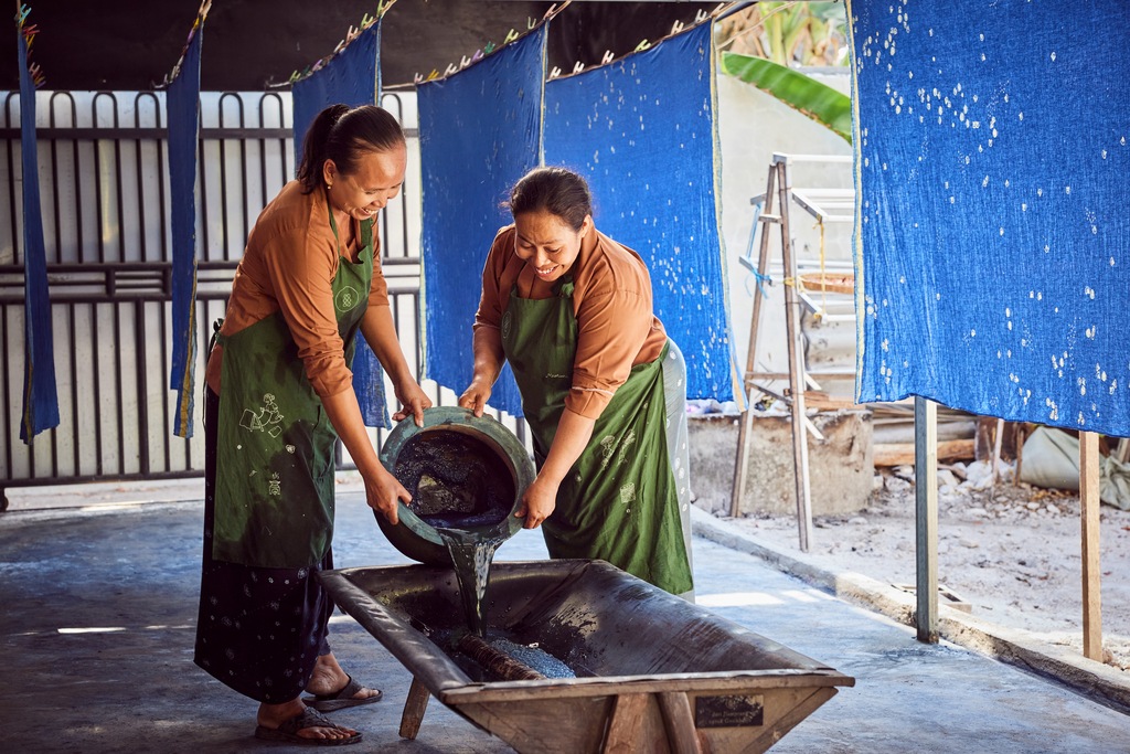 Ibu Sri and Ibu Muntiani prepare a bath for dyeing fabrics in one of SukkhaCitta's craft schools in Rumah, East Java. The textiles hanging behind them are decorated with floral batik designs.
©Rolex / Sébastien Agnetti