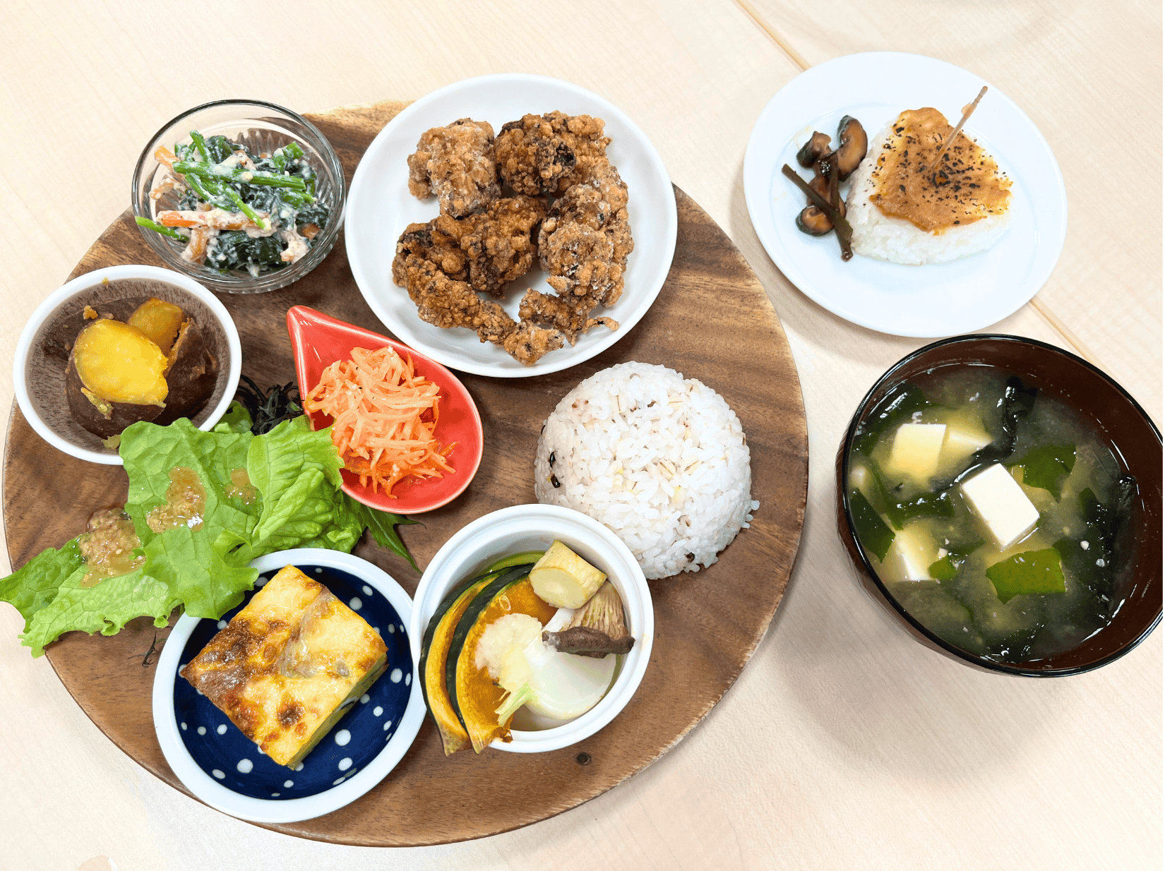 Japanese lunch with miso soup, rice ball, salad, chicken and more