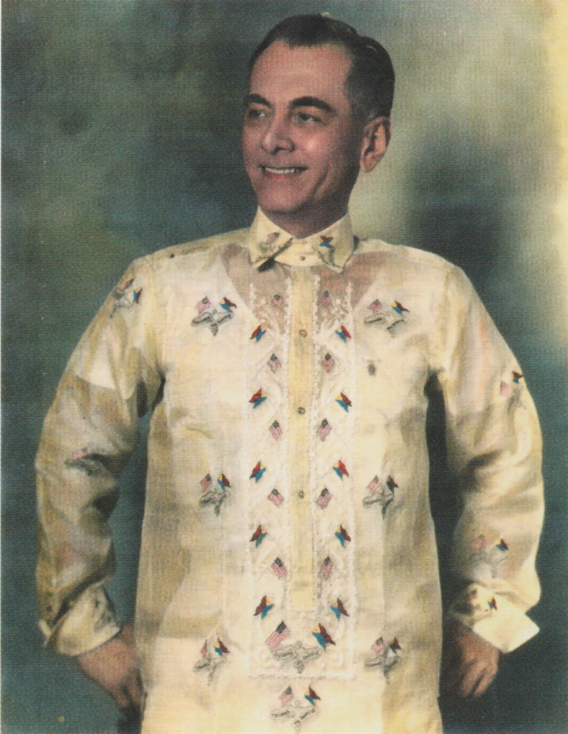 A colorized photo of Manuel L. Quezon wearing a specially-made Commonwealth Barong Filipino after his inauguration ceremony, featuring embroidered motifs of crossed Philippine and US flags, as well as the Tydings-McDuffie Act