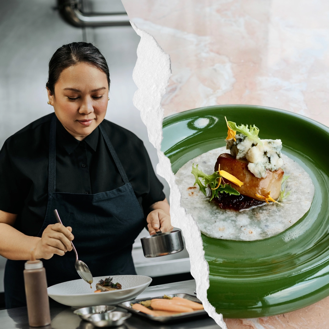 Chef in a black uniform plates a dish in a professional kitchen.