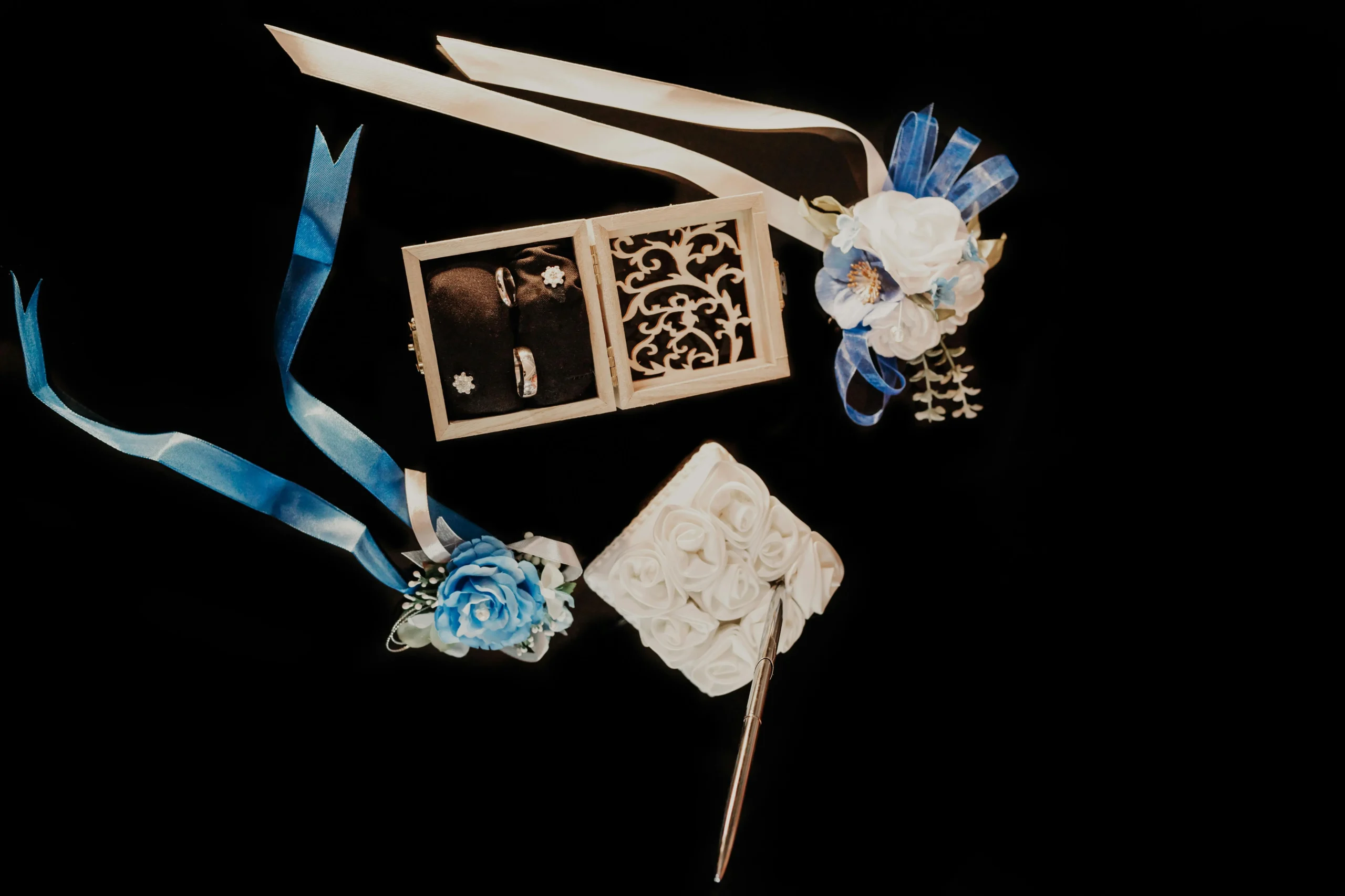 Flat lay of blue and white wedding invitations, flowers, and stationery arranged on a marble tabletop.