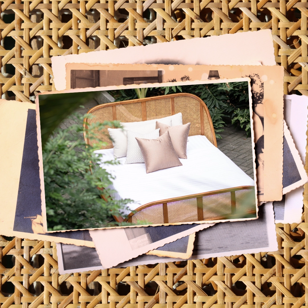 Outdoor rattan bed with white bedding and beige pillows in a garden; a stack of vintage photos sits behind.