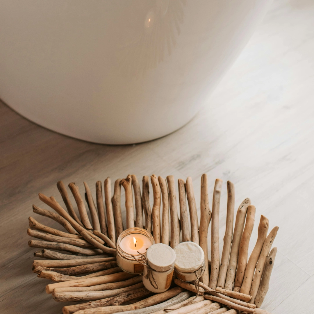 Rustic driftwood centerpiece with a lit candle and small jars on a light wooden surface.