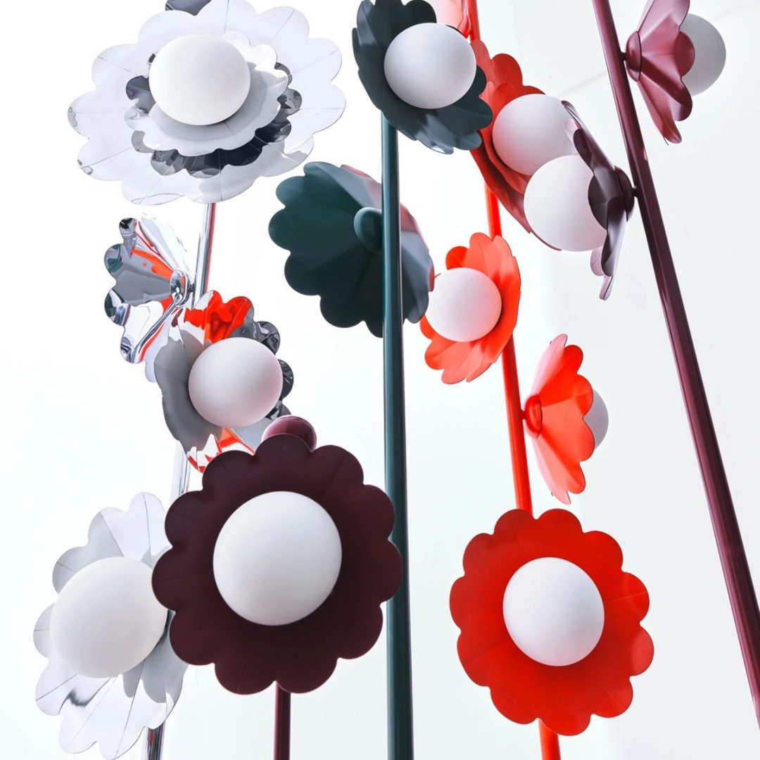 Abstract flower sculpture with red, white, and dark petals on tall colored stems.