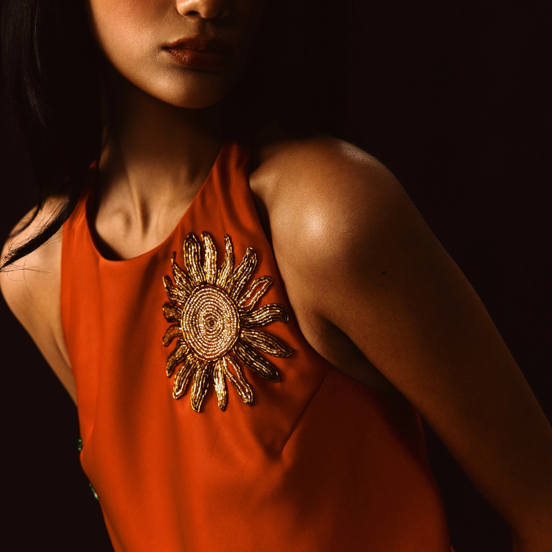 An orange top with an embroidered sun by Atelier Carlene