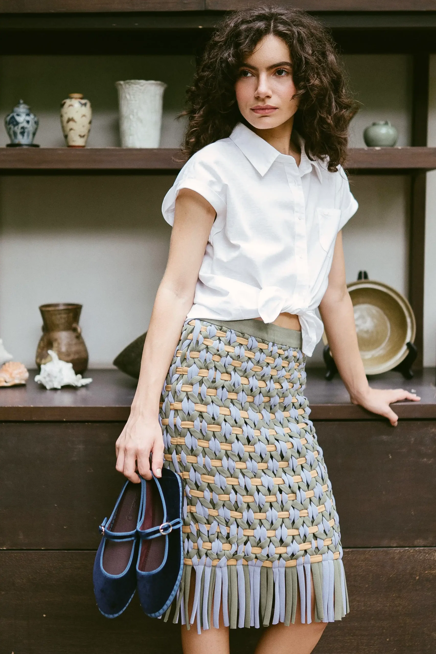 A photo of a model wearing Sari Lazaro skirt and holding Flabelus shoes from the Sari Lazaro x Flabelus pop-up campaign