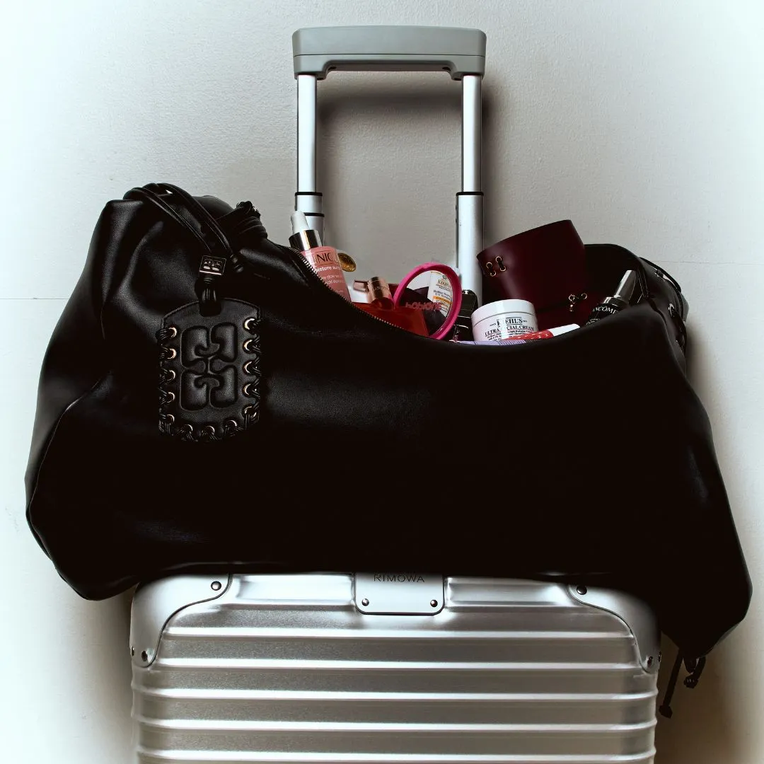 Travel-Sized Beauty Items To Take On Your Next Trip Double XL Hobo Bag by GANNI; Original Compact Case in Silver by RIMOWA; Moisture Surge Active Glow Serum 30m by CLINIQUE; Idole Fragrances by LANCÔME; All-over Multiuse Cream Palette in Malibu Melon by POPIQUE; Better Screen UV Serum by KIEHL’S; Ultra Facial Cream by KIEHL’S; Genifique by LANCÔME.