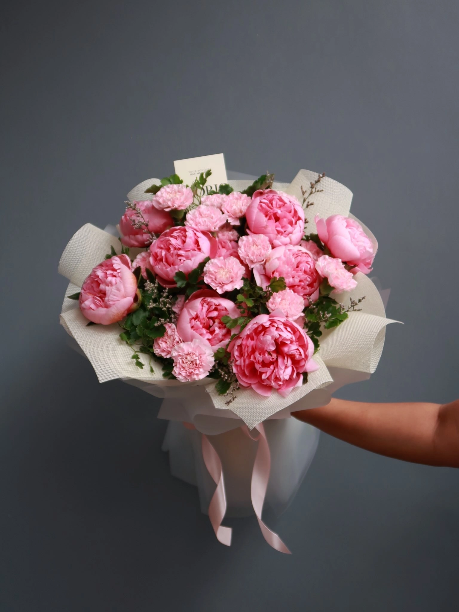Pink peonies traditionally symbolize bliss and prosperity, while carnations represent eternal love