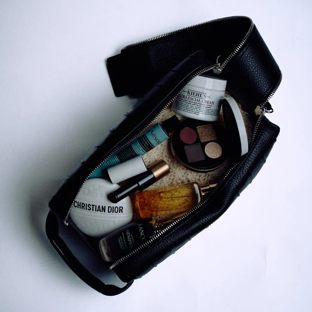 travel kit Travel-Sized Beauty Items To Take On Your Next Trip Leather Toiletry Case in Black by RIMOWA; Ultra Facial Cream by KIEHL’S; Reverence Aromatique Hand Balm by AESOP; Perfume Oil in Cardamusc by HERMÈS; Advanced Génifique Face Serum by LANCÔME; Le Baume by DIOR; Eye Shadow Quartet in Ombres Mordorées by HERMÈS; Silky Lipstick Shine in Rouge H by HERMÈS
